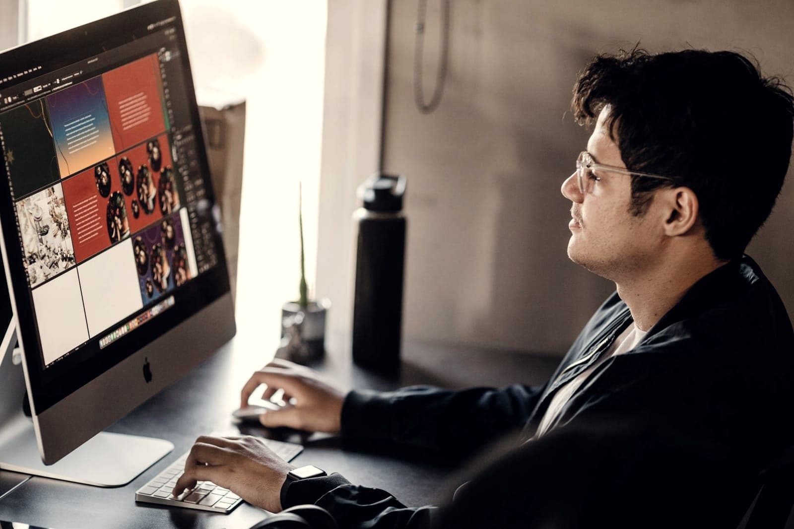 Graphic designer working at an iMac displaying a colorful brand layout
