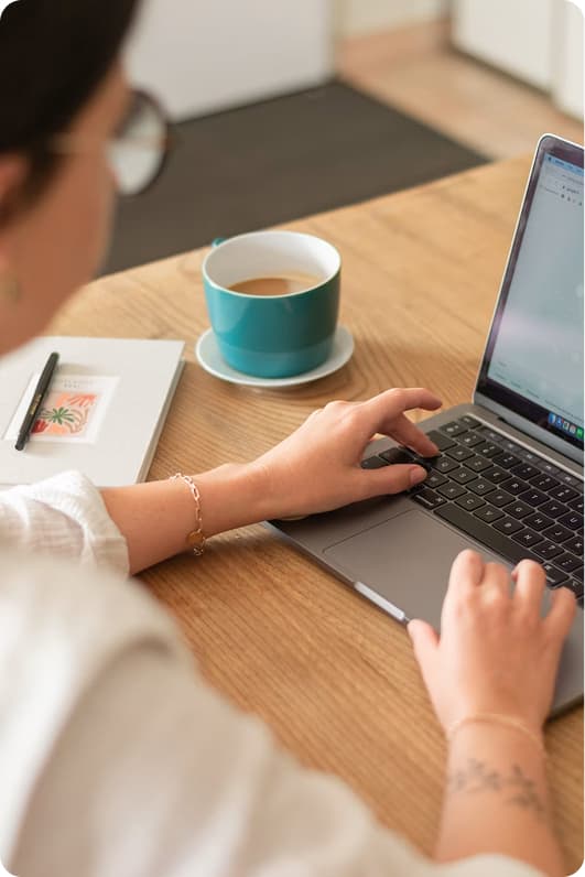 A freelancer working at a laptop with a cup of coffee on a wooden desk